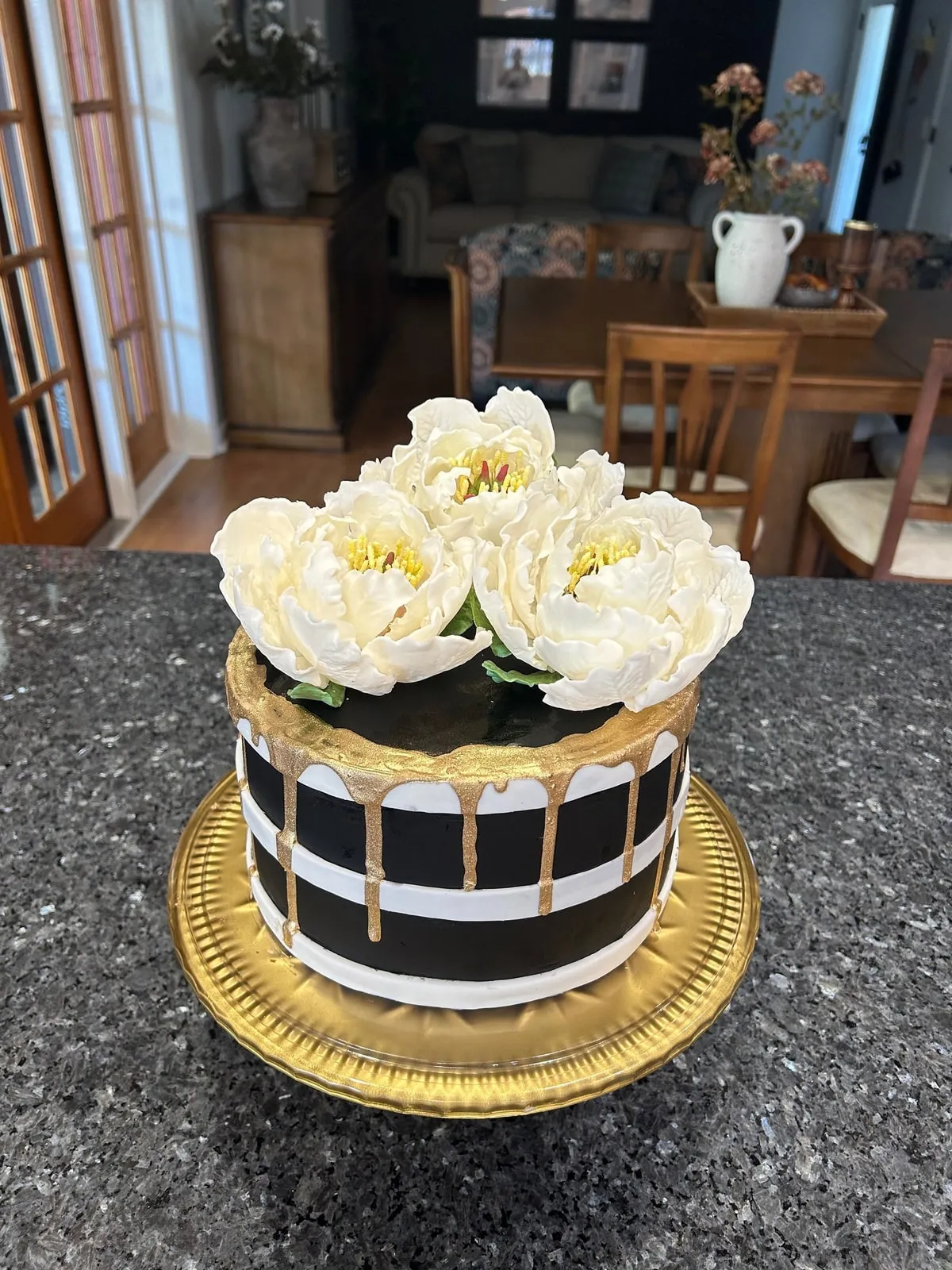 Black and gold striped cake topped with large ivory sugar peonies