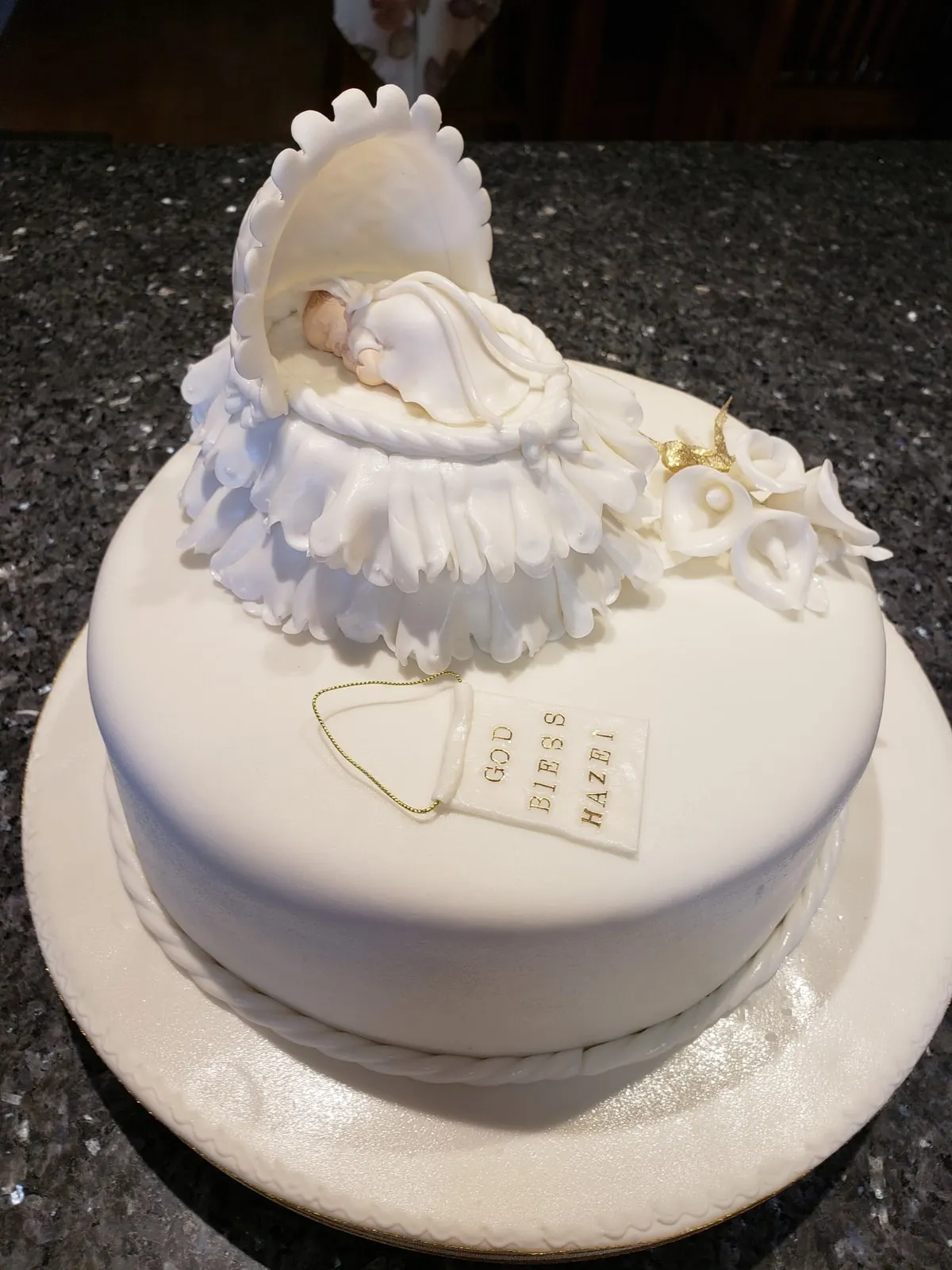 White christening cake topped with a hand modelled sugar baby in a blanket
