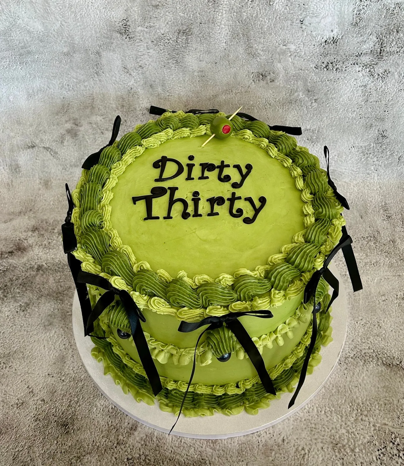 Lime green Dirty Thirty birthday cake with piped shell borders and black ribbon