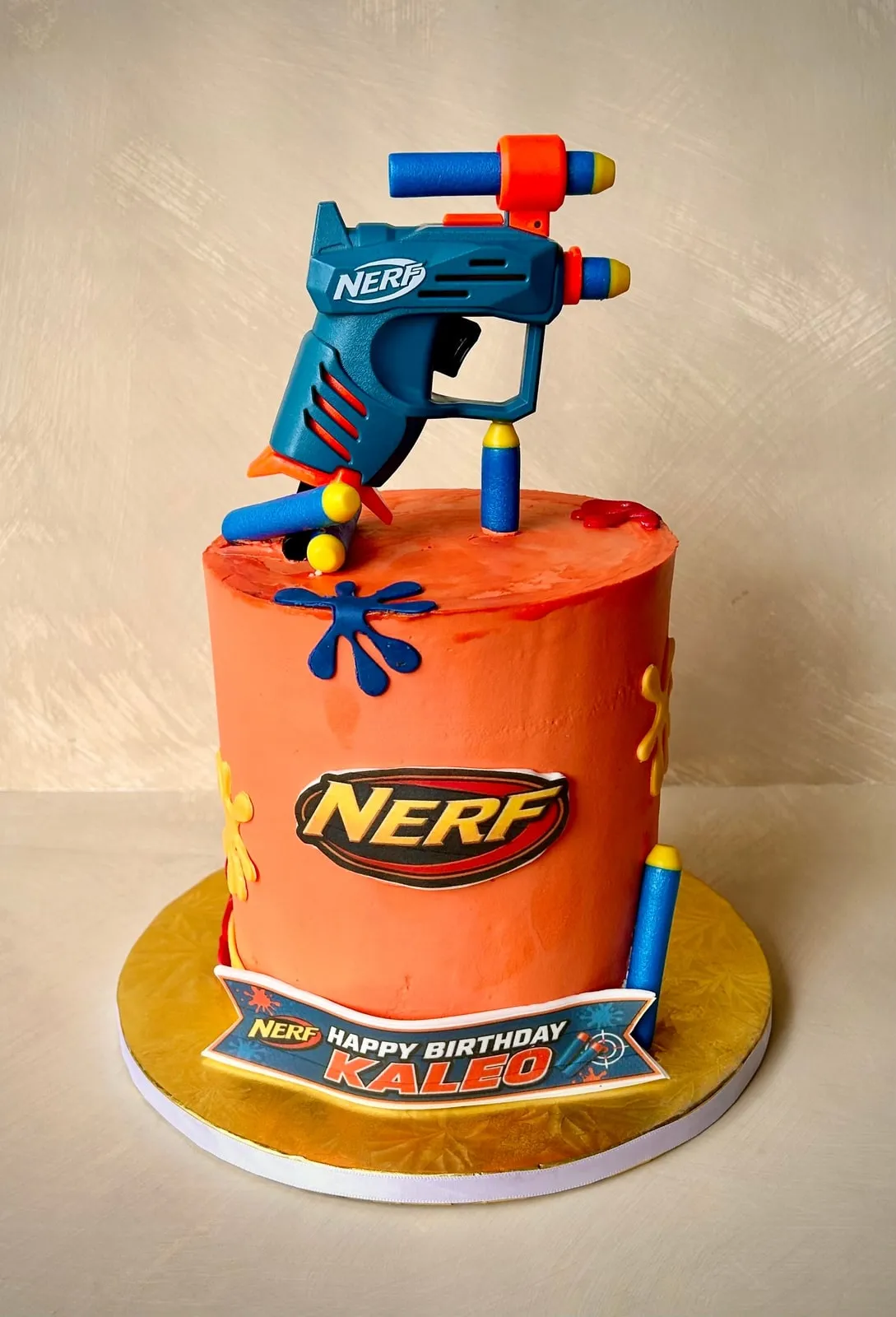 Orange Nerf themed birthday cake with a sculpted fondant blaster on top