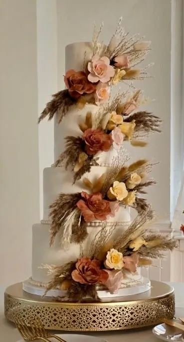 Tall four tier wedding cake with cascading dried florals and pampas grass