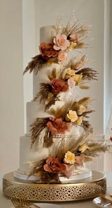 Tall four tier wedding cake with cascading dried florals and pampas grass
