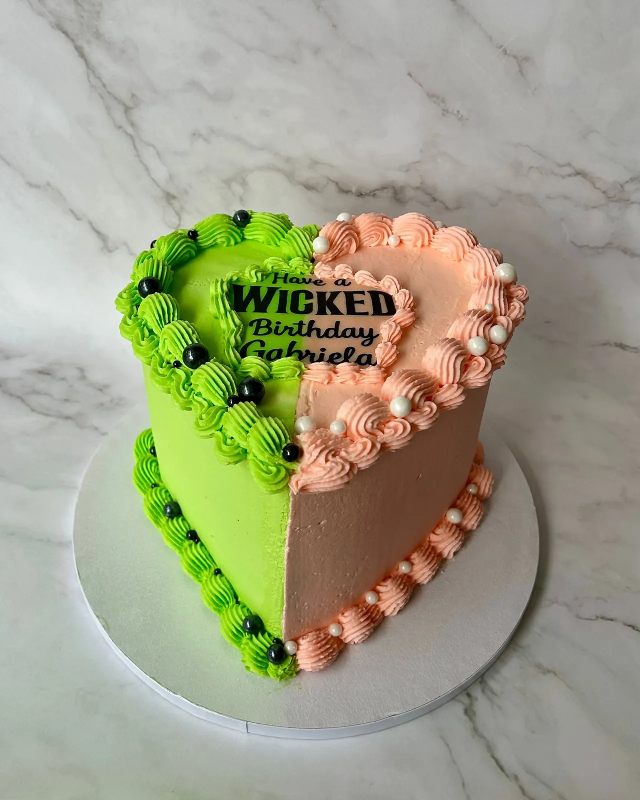 Wicked themed birthday cake split in green and pink with piped shell borders